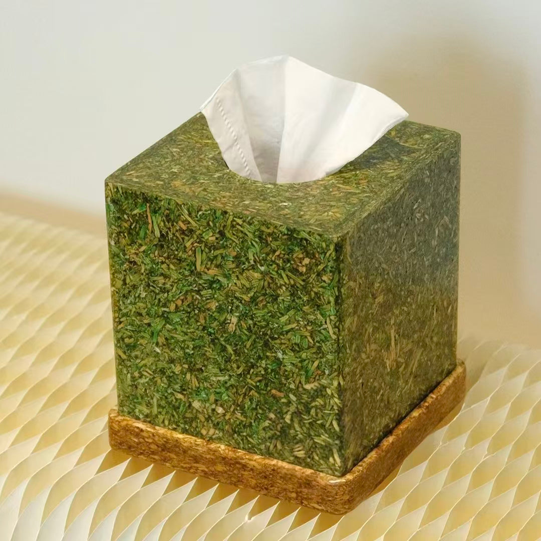  A minimalist square tissue box cover crafted from compressed tea-fiber board, showcasing a rich raw tea-leaf texture on a textured tabletop.