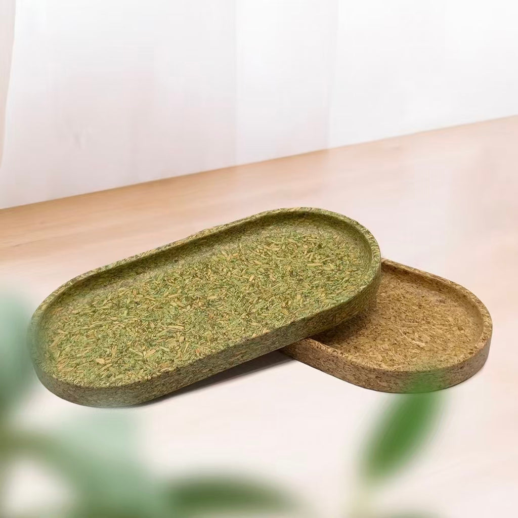 Pairs of eco-friendly oval trays made from recycled tea dregs in natural green and brown colors on a wooden table.
