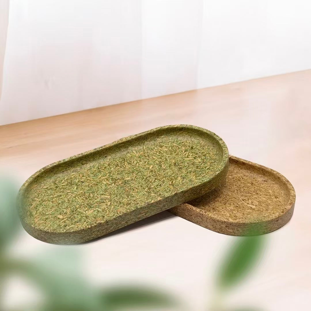 Pairs of eco-friendly oval trays made from recycled tea dregs in natural green and brown colors on a wooden table.
