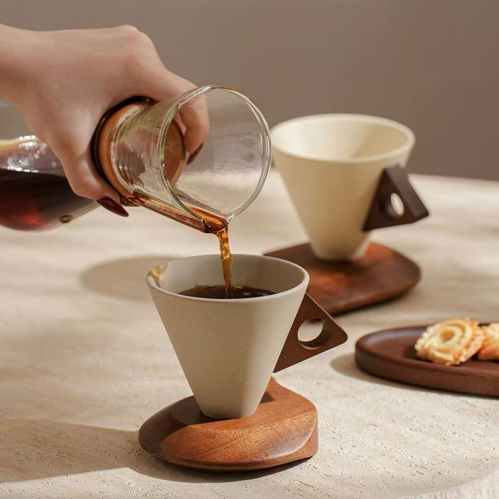 Pouring coffee into geometric cone stoneware mug with wooden handle, modern home coffee station
