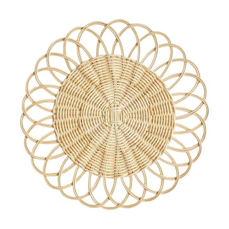  A top-down view of a handcrafted natural rattan placemat featuring an elegant floral petal woven border on a clean white background.