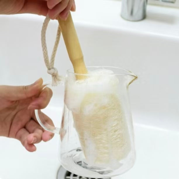 Natural loofah cup brush cleaning glass pitcher at kitchen sink, practical bottle washing tool