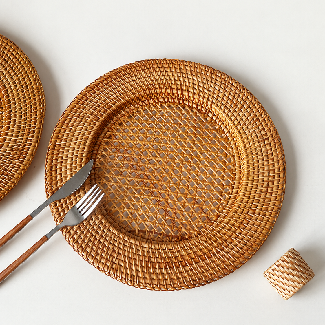 Rustic table setting with natural rattan placemat, wooden cutlery, and woven napkin ring