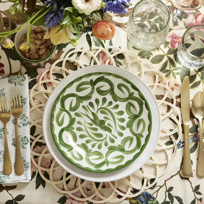  A beautiful rustic dining setup with fresh flowers and green patterned ceramic bowls styled on the handwoven rattan table mat.