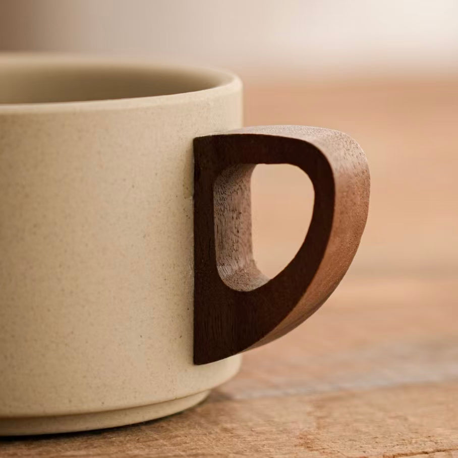 Close-up of hollow cutout walnut wooden handle paired with textured matte stoneware mug