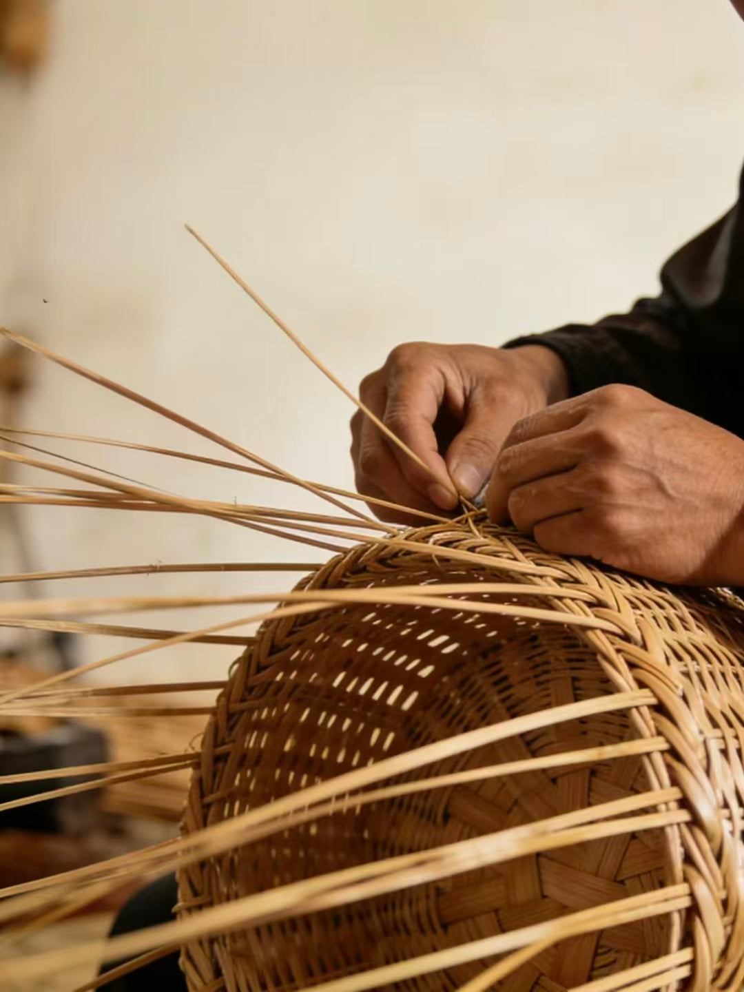 Hands weaving natural plant fibers into a basket form