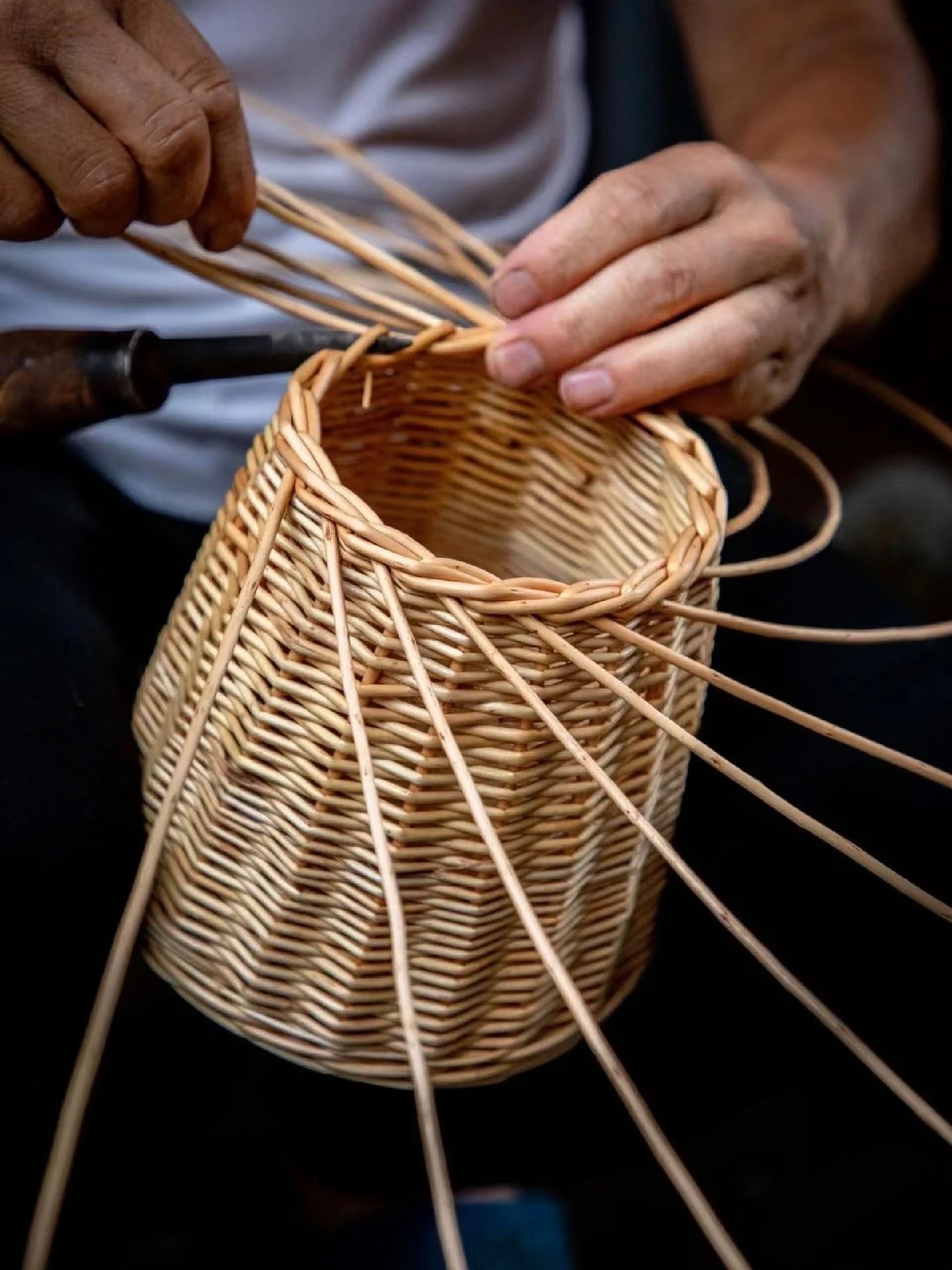 Close-up of hands weaving natural strips into a basket
