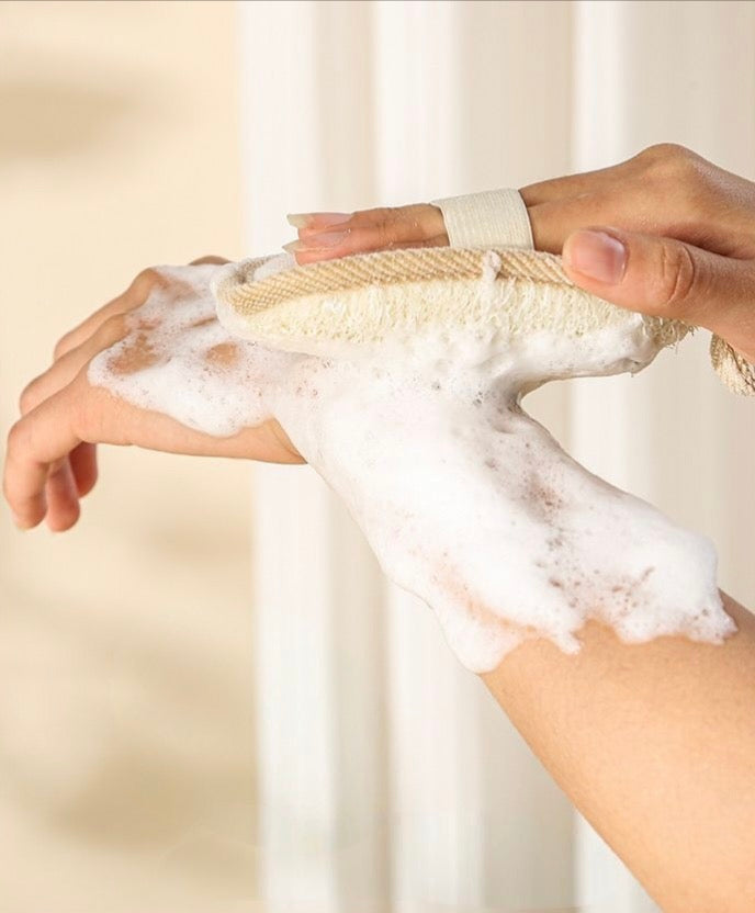 A natural loofah body scrubber being used with soap lather